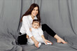 © shunevich - Portrait of beautiful young mother with little daughter posing in studio. Pretty woman hugging adorable baby girl, smiling, looking at camera, motherhood concept
