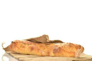 One freshly baked French baguette on jute fabric, close-up, isolated on white.