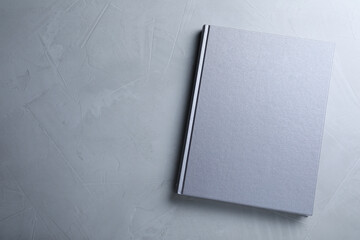 Canvas Print - Closed book with hard cover on grey table, top view. Space for text