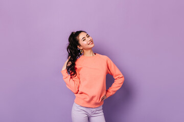 Joyful korean girl posing with hand on hip. Studio shot of stunning asian young lady playing with curly hair.