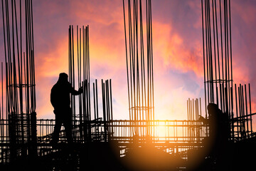 silhouette construction working on high ground over blurred background sunset sky