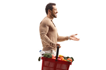 Wall Mural - Profile shot of man holding a shopping basket and gesturing with hand