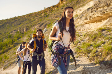 Wall Mural - Group of friends tourists with backpacks traveler in the mountains on a hike hiking along the route in nature in summer.