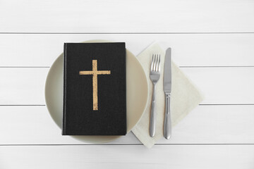 Canvas Print - Plate with Bible and cutlery on white wooden table, flat lay. Lent season