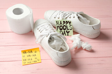 Wall Mural - Shoes with toilet paper and Happy Fools' Day note on pink wooden background