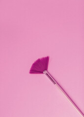 A makeup brush on a pink background.