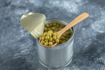 Opened tin green olives and wooden spoon