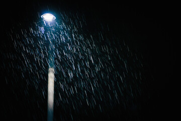 Lamp post and the illuminated rain drops at night. Rain drops/rain streaks. Copy space for text. 