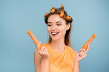 Cheerful Woman Waving Hair With Fresh Carrots Isolated On Blue