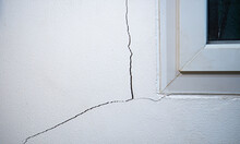 Cracks On The Wall. The Crack In The Cement Wall At The Window Sill, Caused By The Subsidence Of The Ground, Causing A Slit At An Oblique Angle.