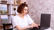 a woman with glasses works at home in a cozy environment remotely at a computer