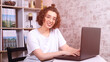 a woman with glasses smiles at a computer, a remote employee in a home office, remotely