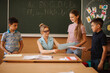 © Aleksandr - Education, elementary school. Learning and people concept - group of school kids with pens and notebooks writing test in classroom