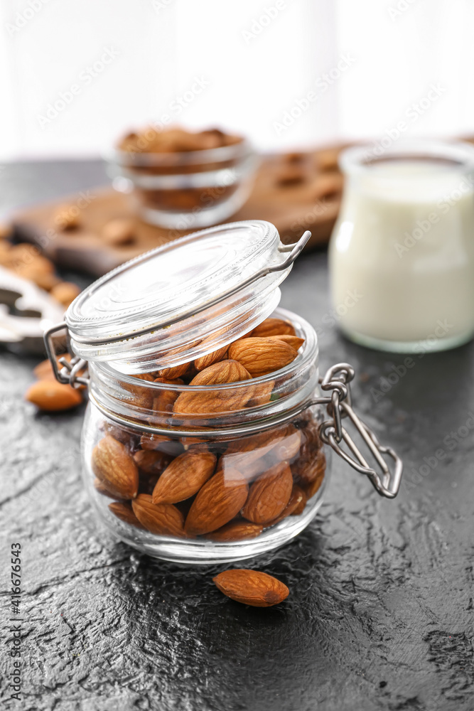 Jar of healthy almonds on dark background