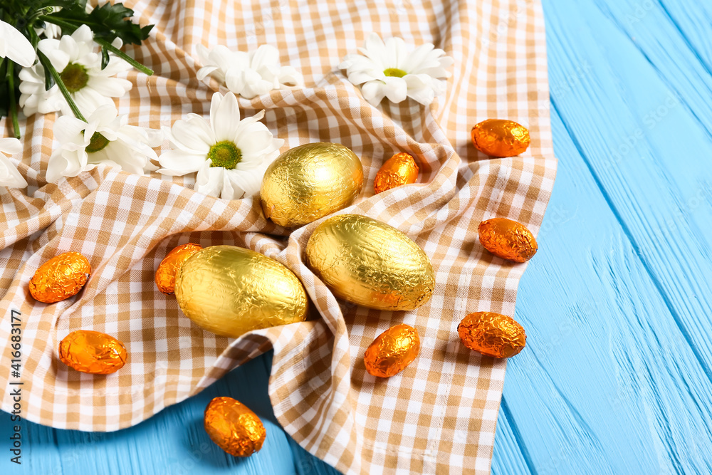 Beautiful composition with chocolate Easter eggs and flowers on color wooden background
