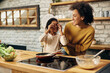 © Drazen - Happy African American mother and daughter having fun while cooking in the kitchen.