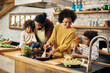 © Drazen - Happy African American family preparing a meal in the kitchen.