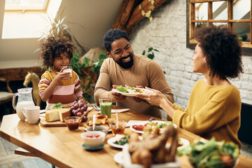 Happy black family enjoying in a meal at dining table at home.