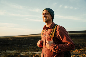 caucasian male hiker walking through wilderness embracing sunrise while enjoying nature