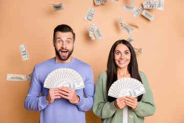 Photo of impressed couple hold money wear sweater isolated on beige color background