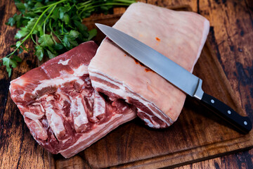 fresh pork belly on a used cutting board resting on an old wooden table