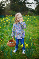 Wall Mural - Three year old girl playing egg hunt on Easter