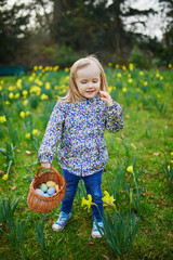 Wall Mural - Three year old girl playing egg hunt on Easter