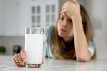 Wall Mural - Woman taking medicine for hangover in kitchen, focus on hand with glass