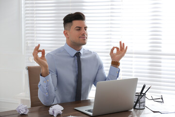 Wall Mural - Businessman meditating at workplace in office. Stress relieving exercise