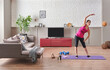 © UnitedPhotoStudio - Sportive woman is doing training at home, purple mat, blue dumbbell, decorative living room concept. Healthy lifestyle.