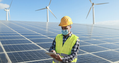 man worker using digital tablet while wearing safety mask at renewable energy farm during coronaviru
