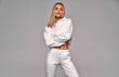 Beautiful sexy blonde woman wear of white set of tracksuit isolated on gray background