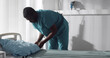 African male nurse changing sheets in hospital ward