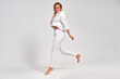 Beautiful blonde woman jumping in the air in white tracksuit isolated on gray background