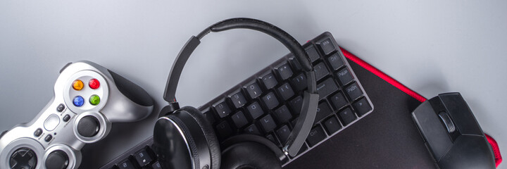 Gaming and gamer devices concept. Gamer work table space background, top view. Keyboard, mouse, gamepad joystick, mouse pad and headphones. on grey table background above with copy space for text