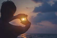 Man Making Frame Round The Sun With Her Hands In Sunrise,Future Planning Idea Concept.