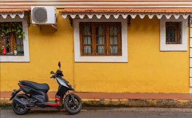 Scooter parked in front of yellow colored wall at fontainhas