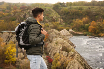 Wall Mural - Traveler with backpack enjoying beautiful view near mountain river. Autumn vacation