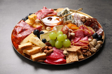 Wall Mural - Plate of different appetizers with honey on grey table, closeup