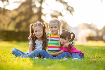 three little girls cuddle in the summer on the lawn. International Children's Day