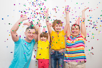 happy family mom, dad and two kids  brother and sister with confetti on colored 
