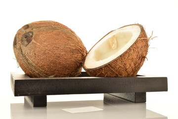 Two halves of ripe organic coconut on a wooden tray, close-up, isolated on white.