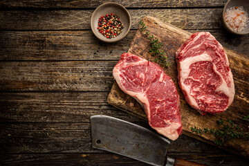 Wall Mural - Variety of Fresh Raw Black Angus Prime Meat Steaks New York, Ribeye and seasoning on wooden background, top view