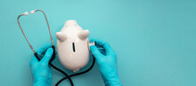 Health Care Cost. Doctor In Surgical Gloves Holding A White Piggy Bank And Stethoscope