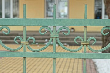 Canvas Print - metal texture from a green forged pattern on  bars of a fence on the street against a brown background