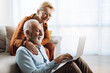 © Goran - Senior couple surfing the Internet on their laptop at home