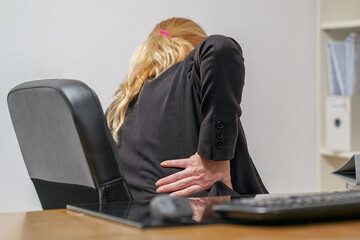 Front view upset businesswoman feeling back pain sitting on office chair touching aching muscle