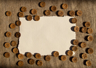 Variety of ethnic tribal African boho brown coconut buttons on brown rustic linen fabric with copy space for text. A background for sewing or handmade shops website or social network page design