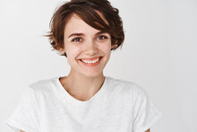 Close Up Portrait Of Cute Girl With Short Hairstyle And Clean Smooth Skin, Smiling Happy At Camera, Standing Against White Background