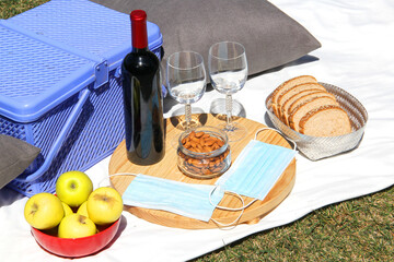 picnic in pandemic. basket with wine and food outdoors in the forest and protective masks